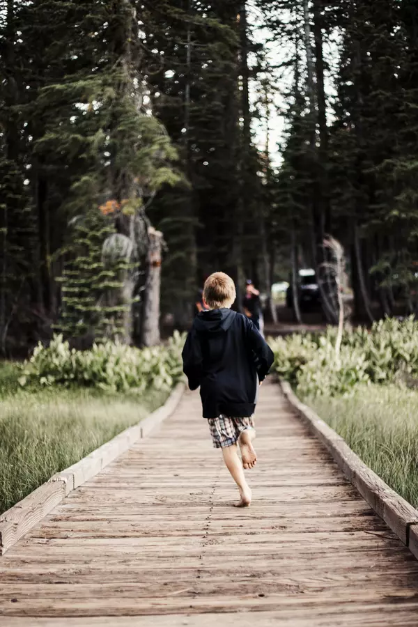 Junge rennt auf einem Holzpfad auf den Ostseewald zu
