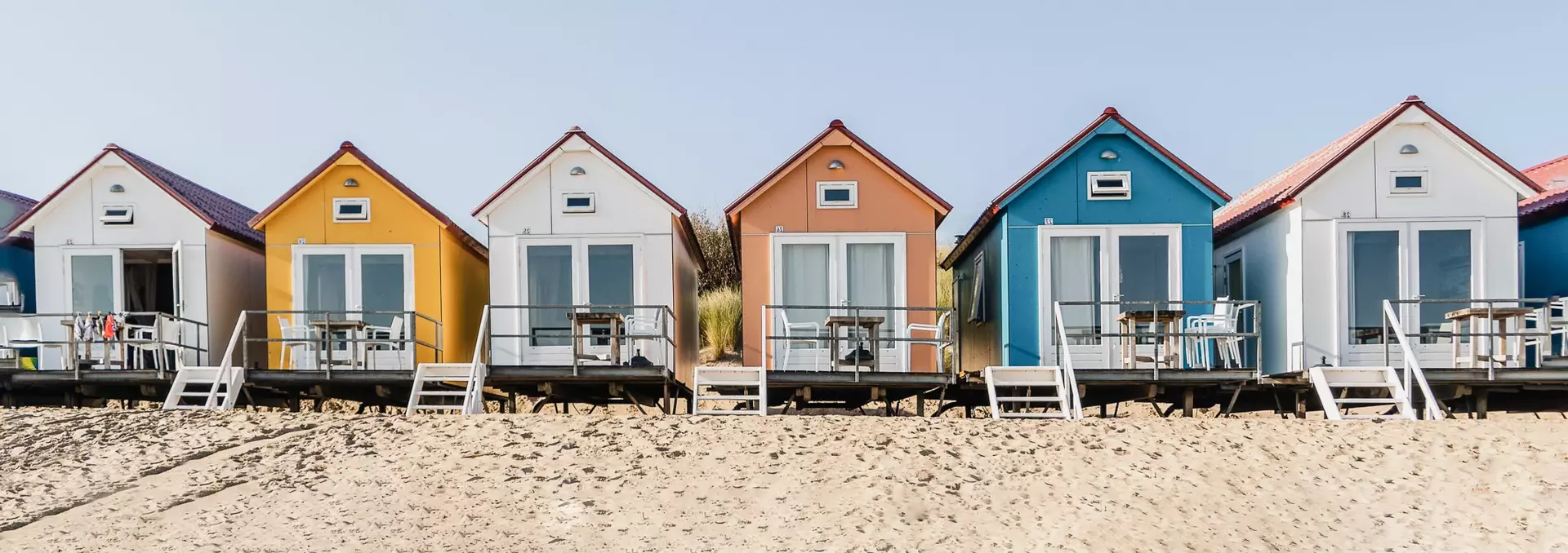 Eine Reihe bunter Ferienhäuschen am Nordseestrand