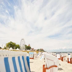 Strandkörbe und Häuser und Riesenrad am Strand von Kühlungsborn