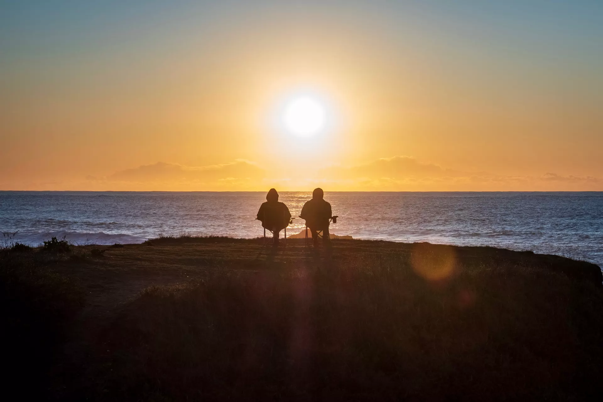 Zwei Angler blicken in den Sonnenuntergang an der Nordsee