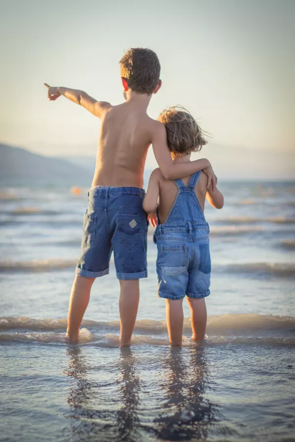 Zwei kleine Kinder schauen umarmt auf die Ostsee